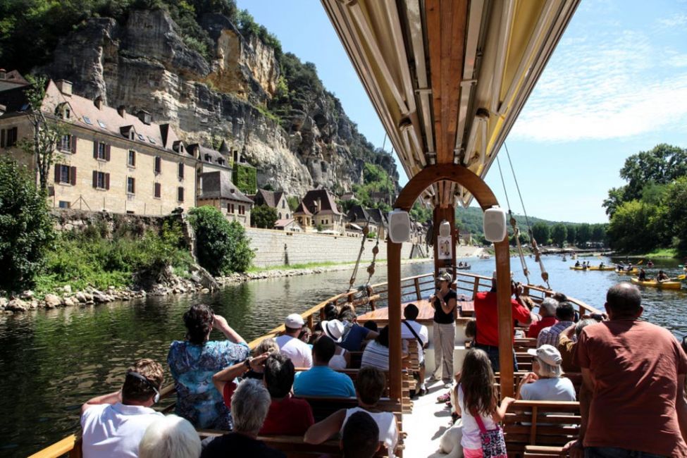 Gabarre boat cruise in La Roque Gageac with view of cliffside houses and river