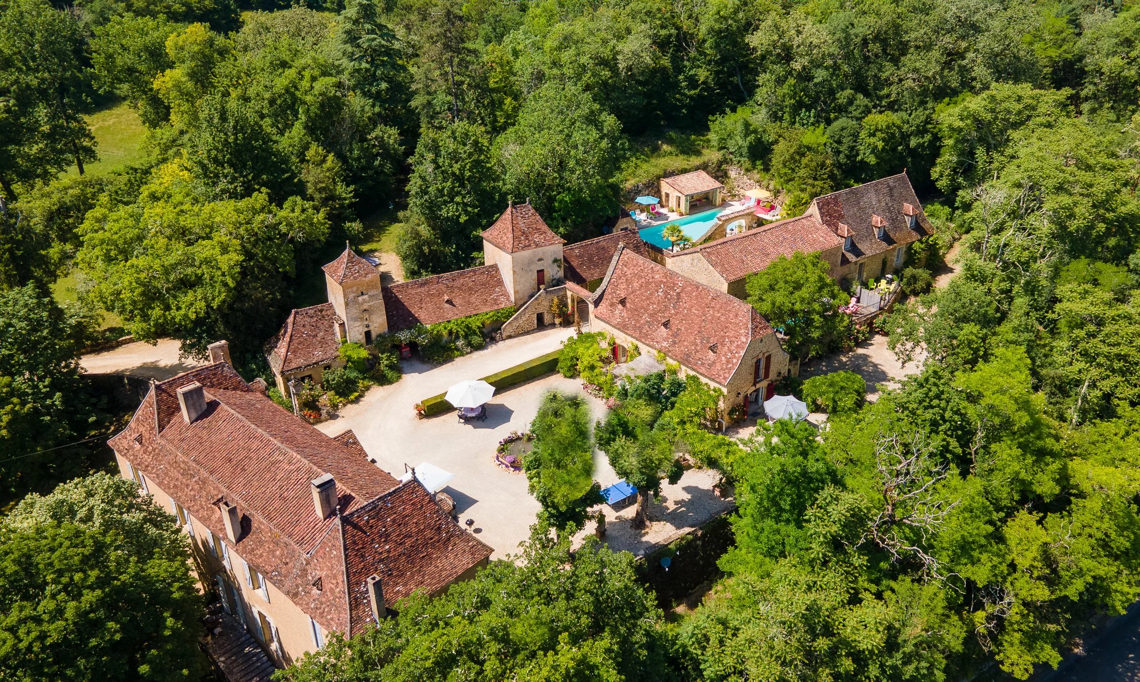 raditional Dordogne stone houses with terracotta roofs and courtyard surrounded by greenery